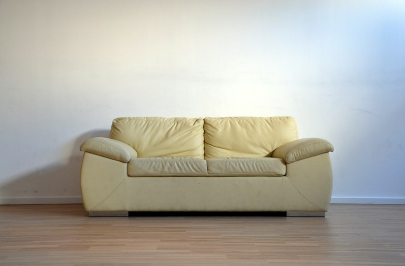 Before: Faded wooden sofa with ripped upholstery